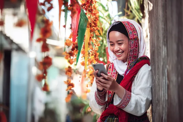 A player using their smartphone during a festive local event, representing 777D’s fully mobile-friendly casino.